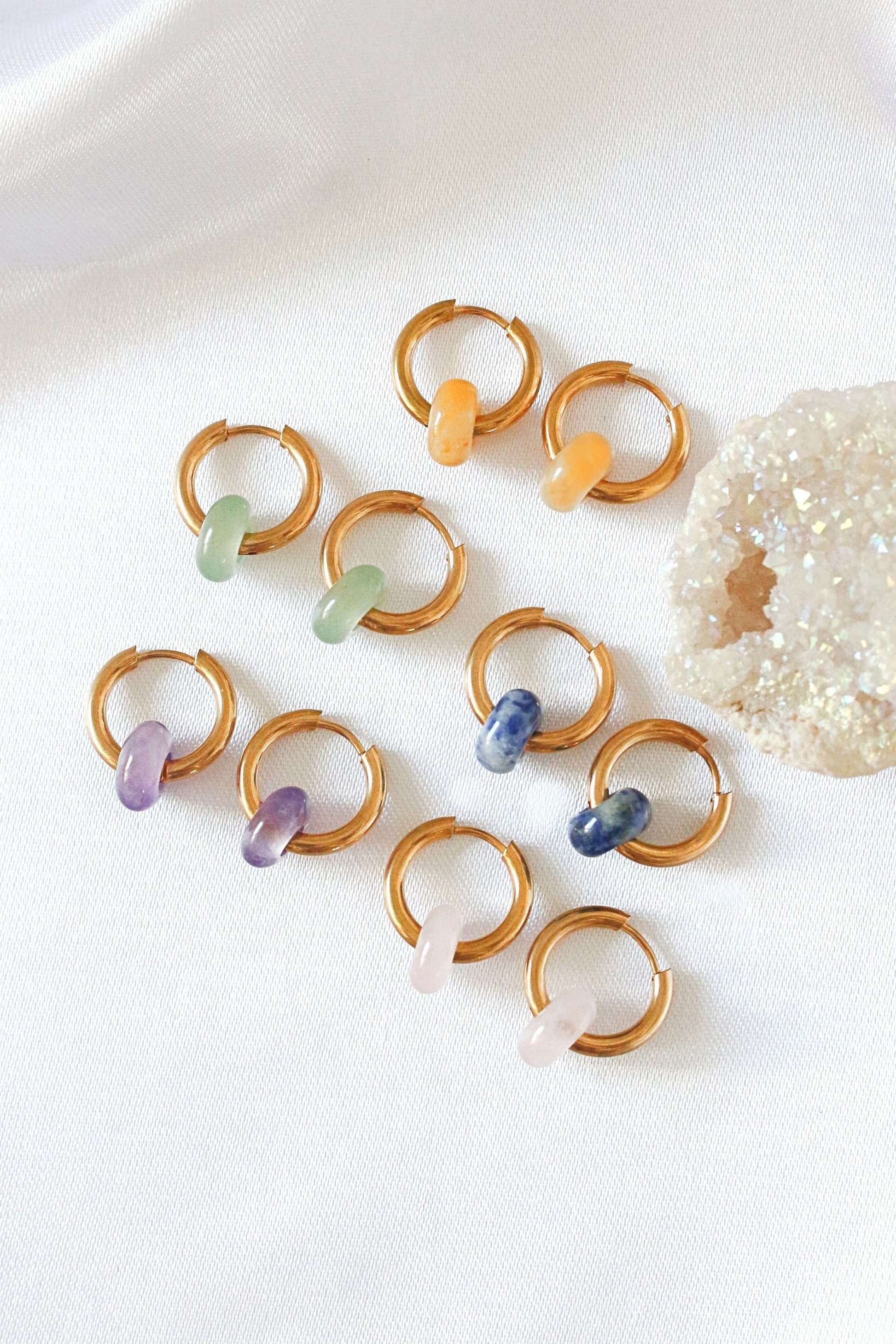 Gold earings with colorful beads on a white surface