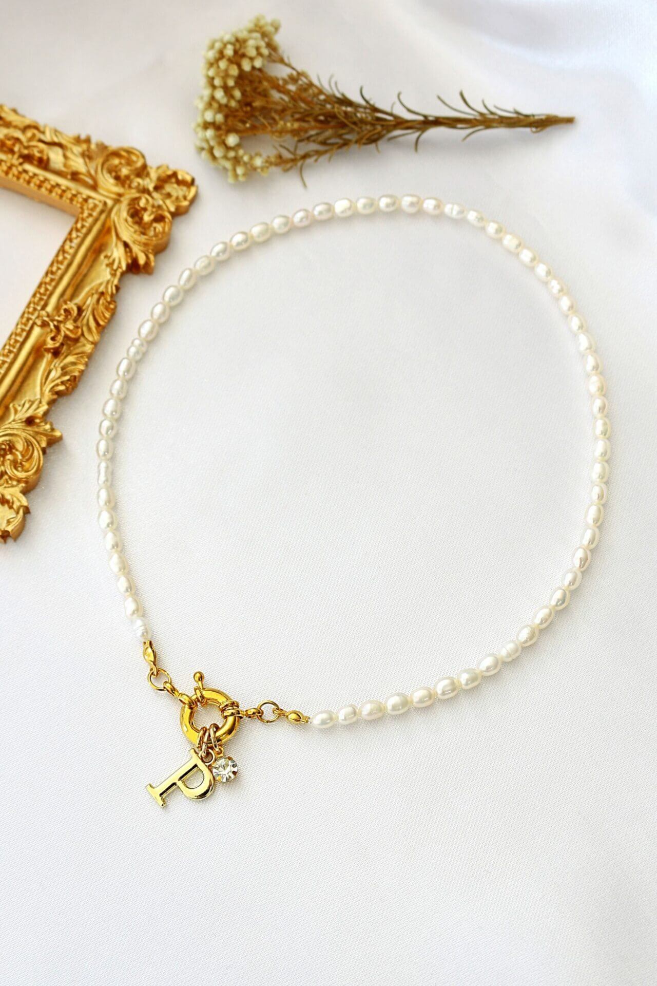 Pearl bracelet with a gold charm on a white surface with decorative elements.