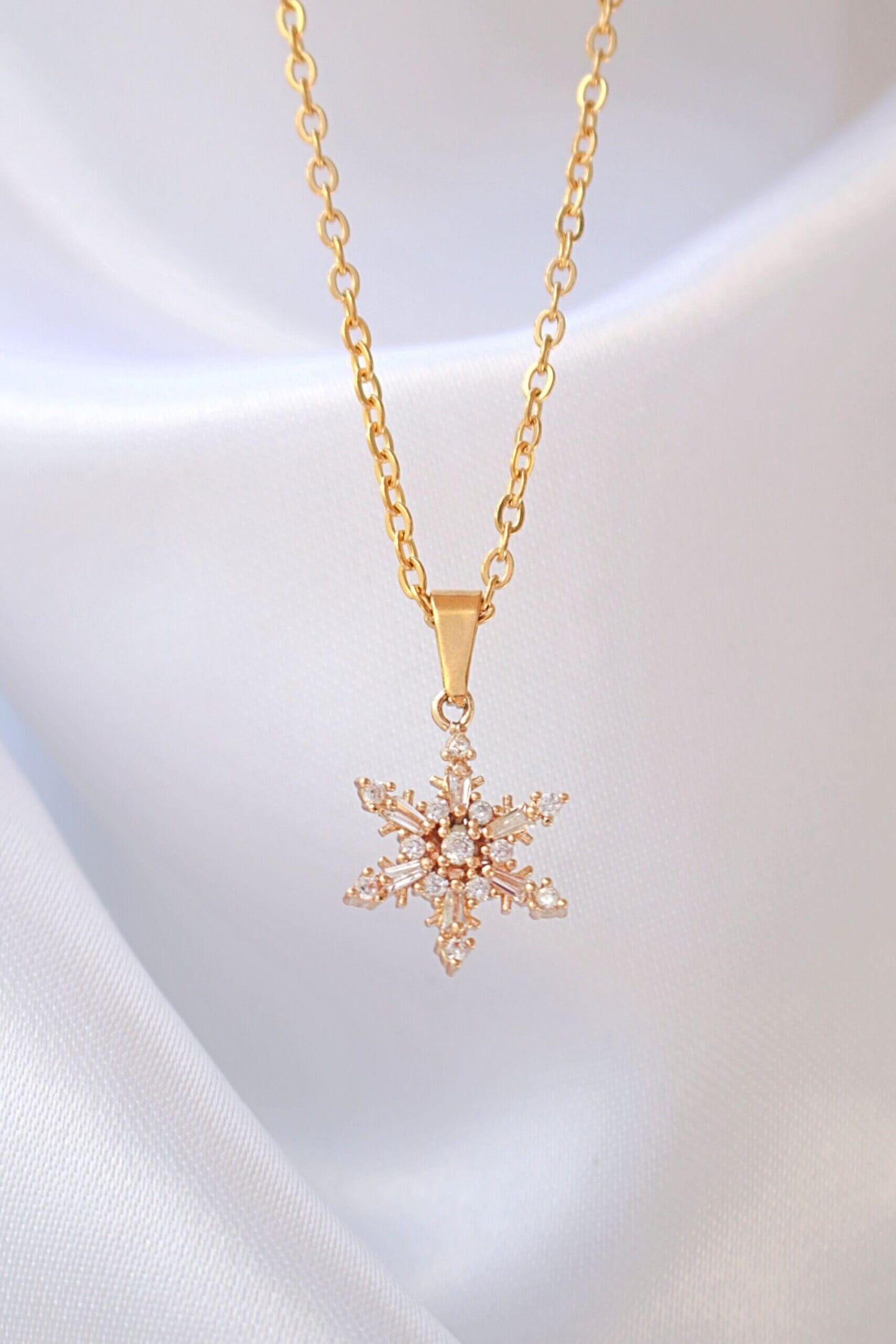 Gold necklace with a snowflake pendant on a white background