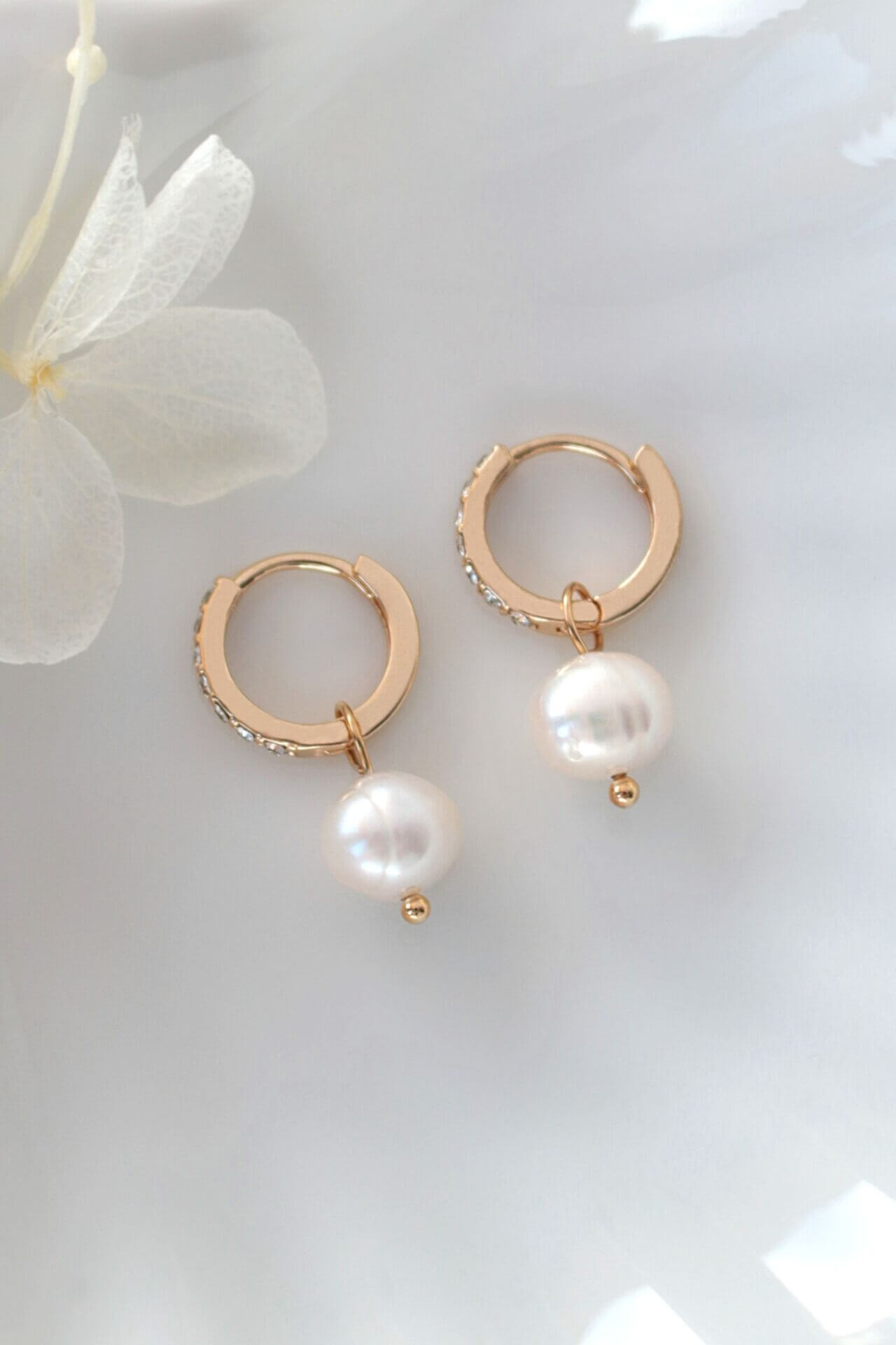 Gold hoop earrings with pearls on a light background
