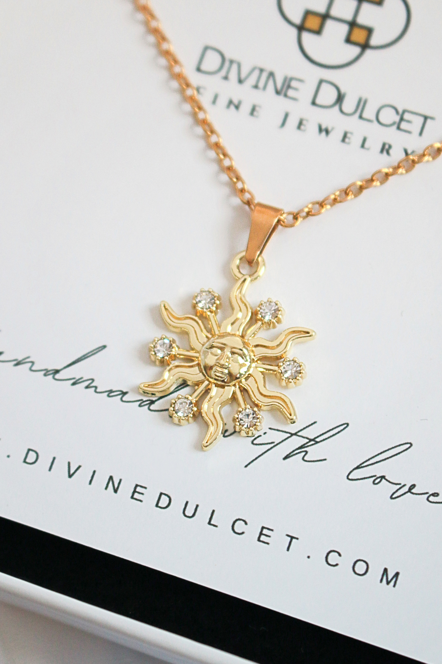 Gold sun-shaped pendant necklace on a Divine Dulcet card