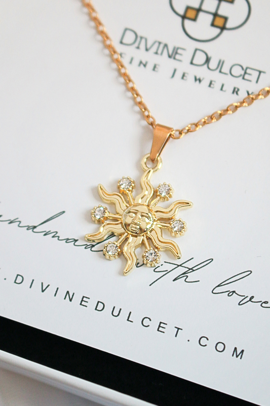 Gold sun-shaped pendant necklace on a Divine Dulcet card