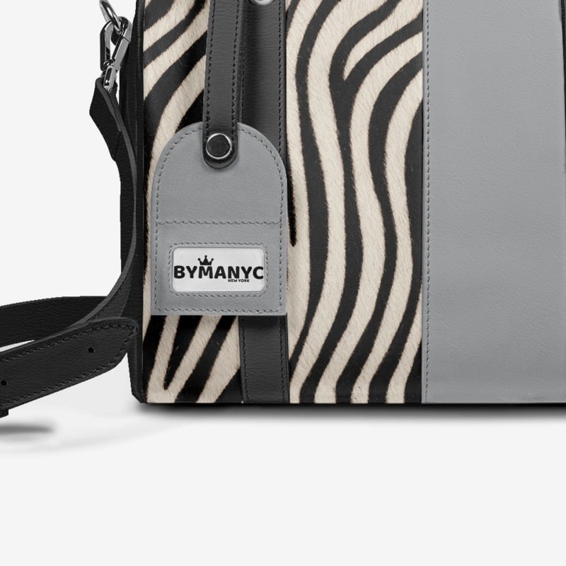 Handbag with zebra pattern and gray body, featuring a ByManyC tag.