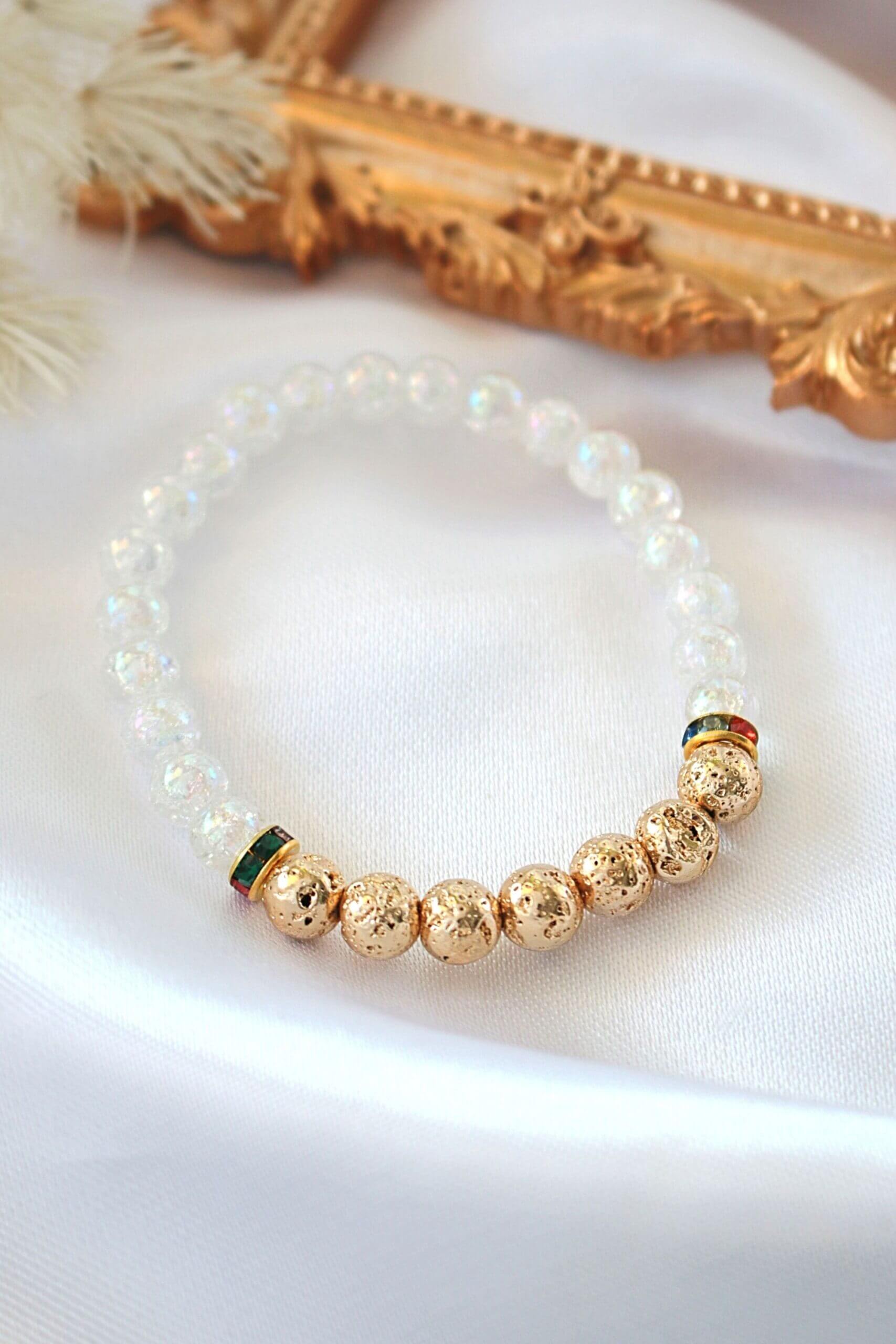 Pearl and gold beaded bracelet on a white surface with a decorative gold frame in the background.