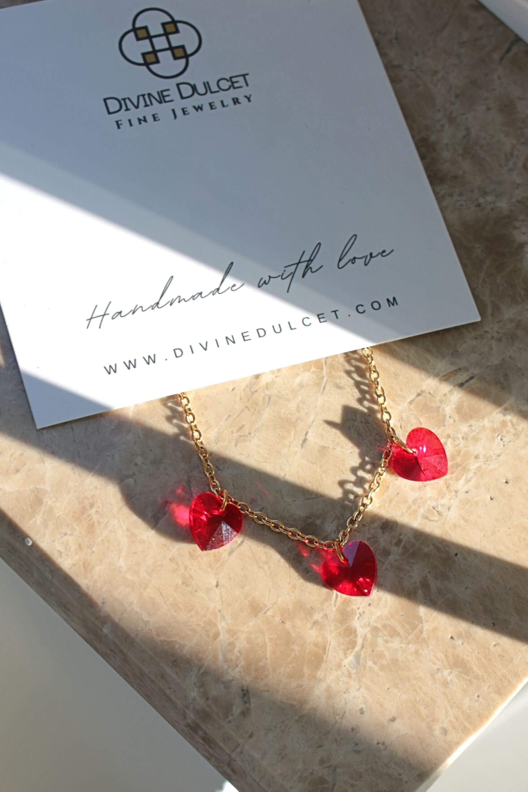 Gold necklace with red heart pendants on a Divine Dulcet card.