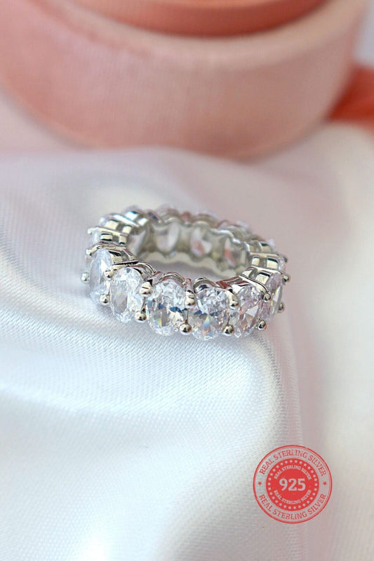 Silver ring with clear stones on a white fabric background, featuring a '925' stamp.