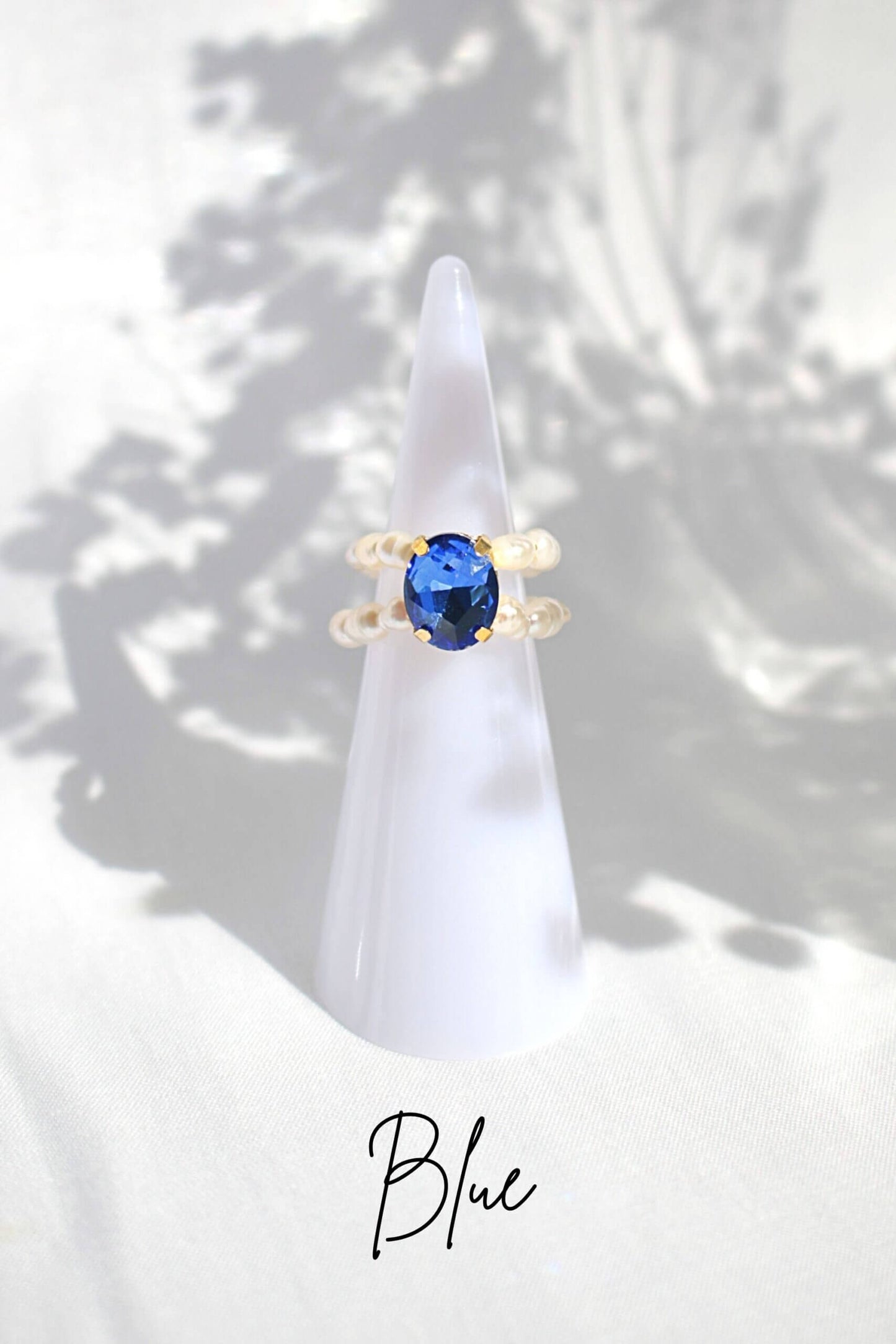Gold ring with a blue gemstone on a white cone against a light background