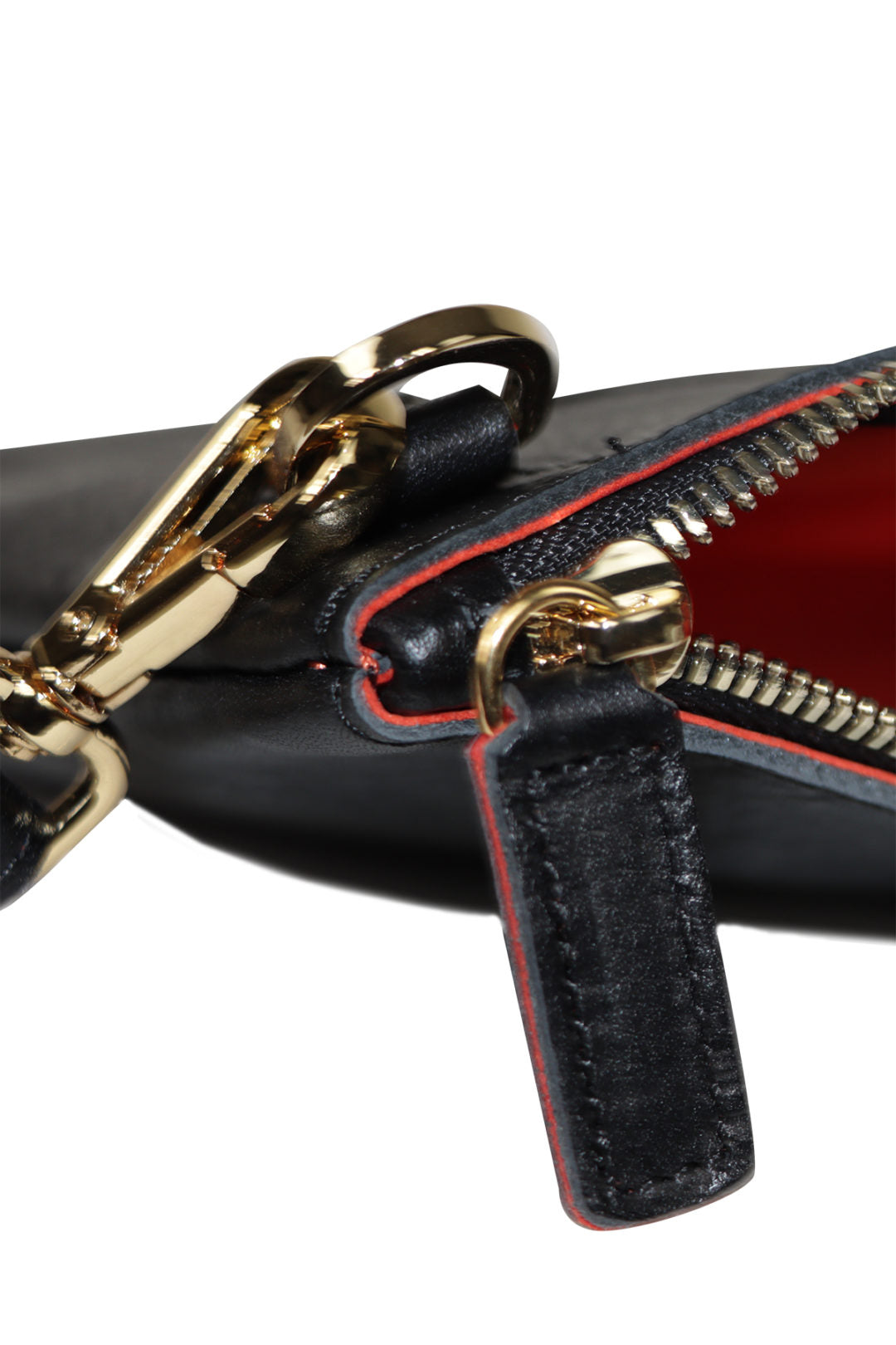 Close-up of a black leather handbag with gold zipper pull and chain detail on a white background