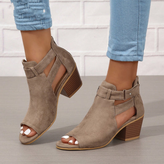 Brown open-toe shoes with block heels worn with light blue jeans on a neutral background