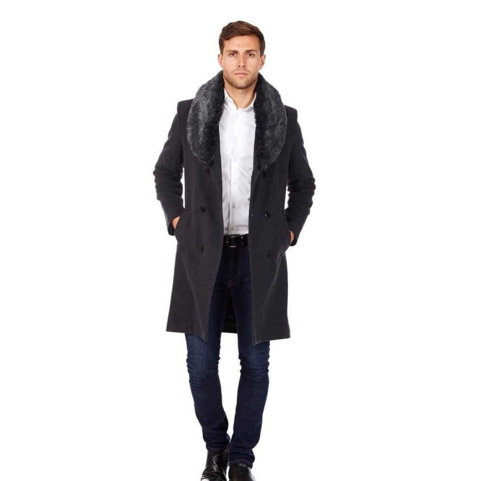 Man wearing a long dark coat with fur collar on a white background