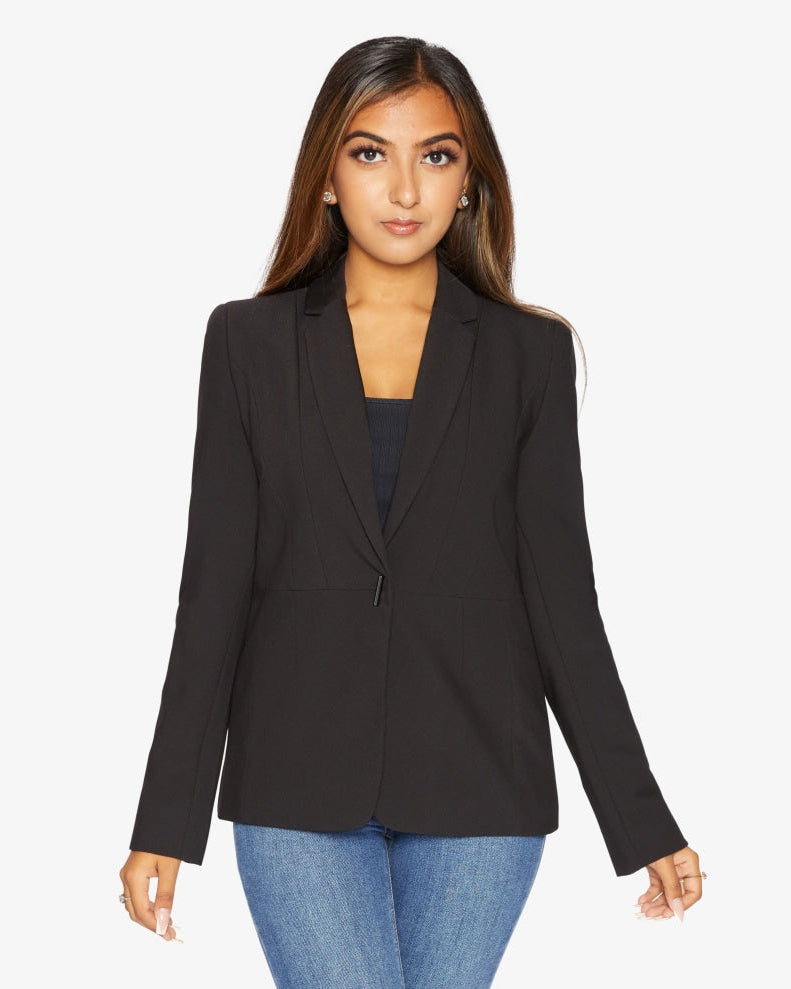 Woman wearing a black blazer over a blue top on a white background