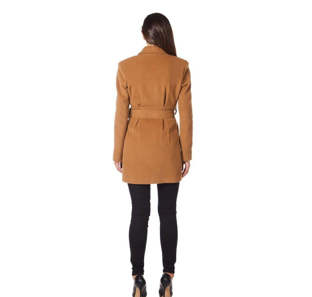 Woman wearing a tan coat with a belt on a white background