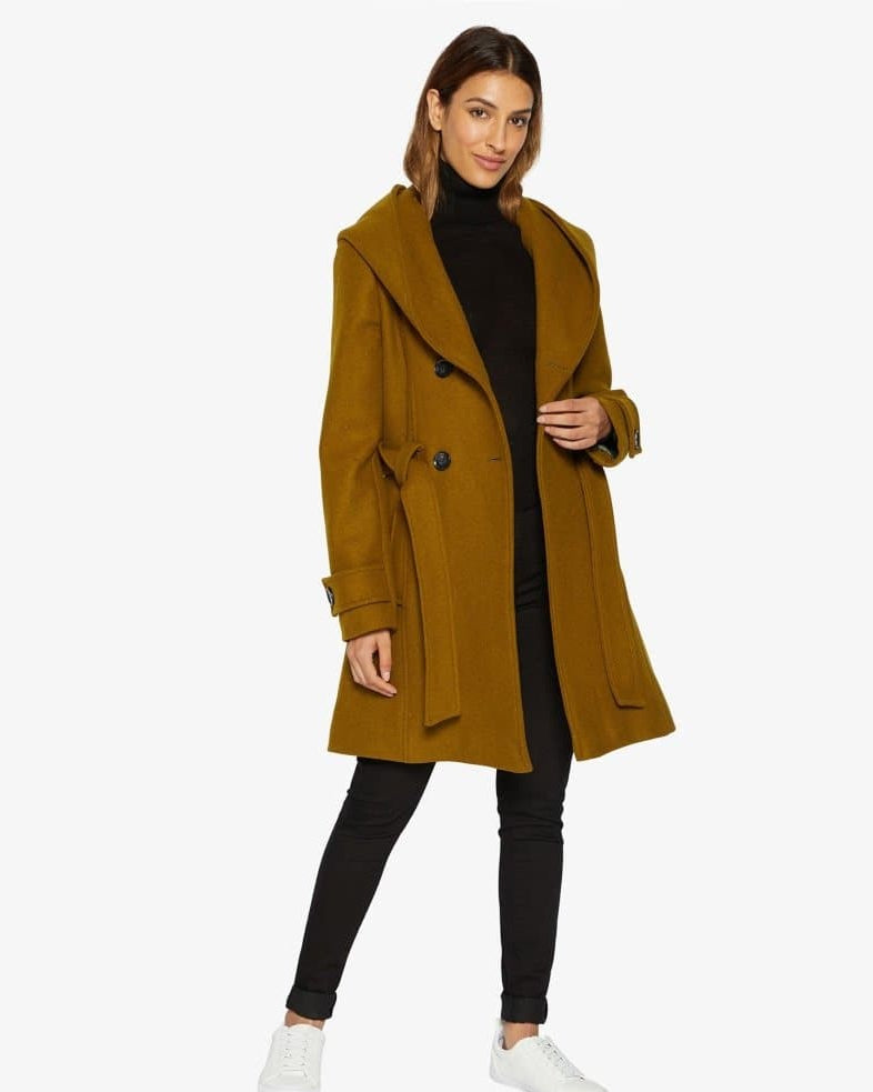 Woman wearing a mustard yellow coat on a white background.