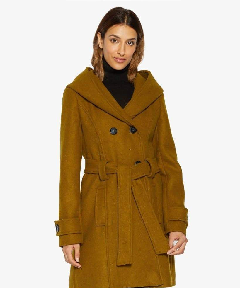 Woman wearing a mustard yellow coat with a white background