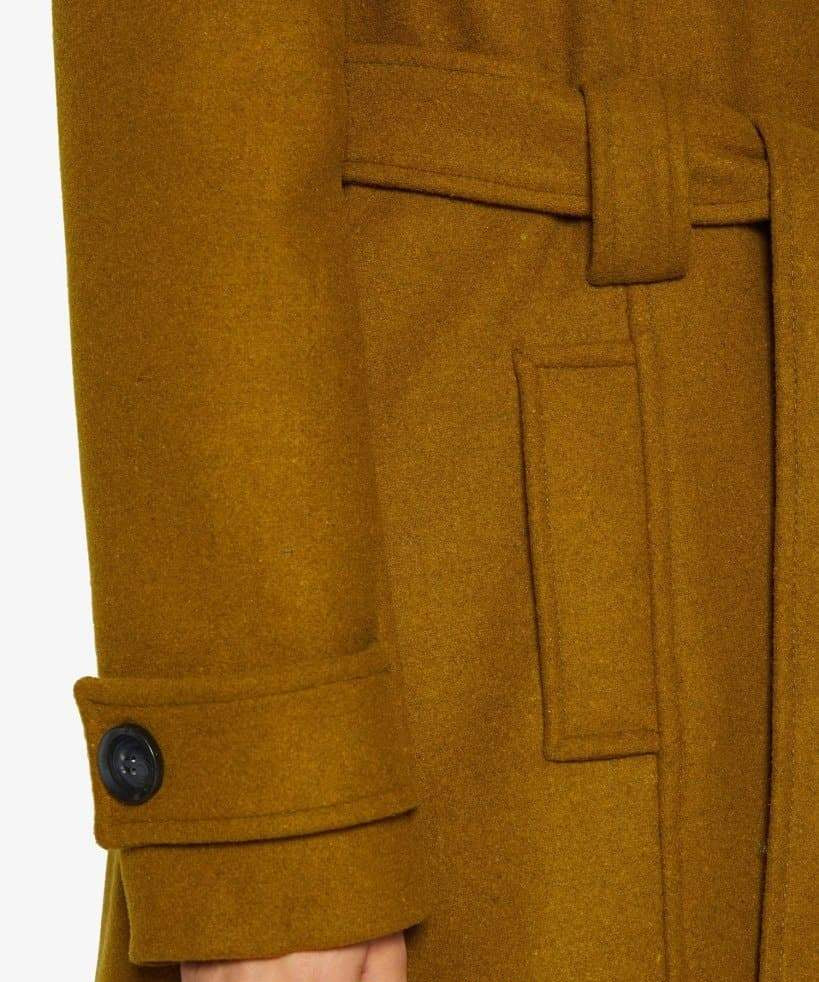 Close-up of a mustard yellow coat with a button and pocket detail.