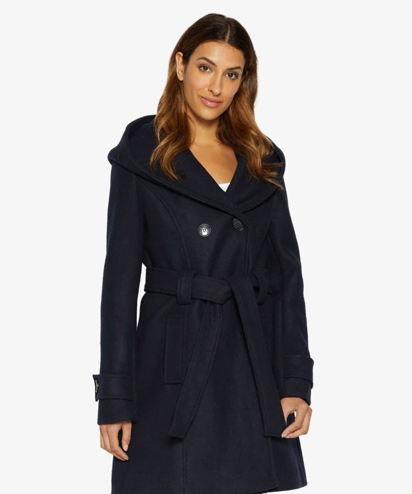Woman wearing a navy blue coat with a white background