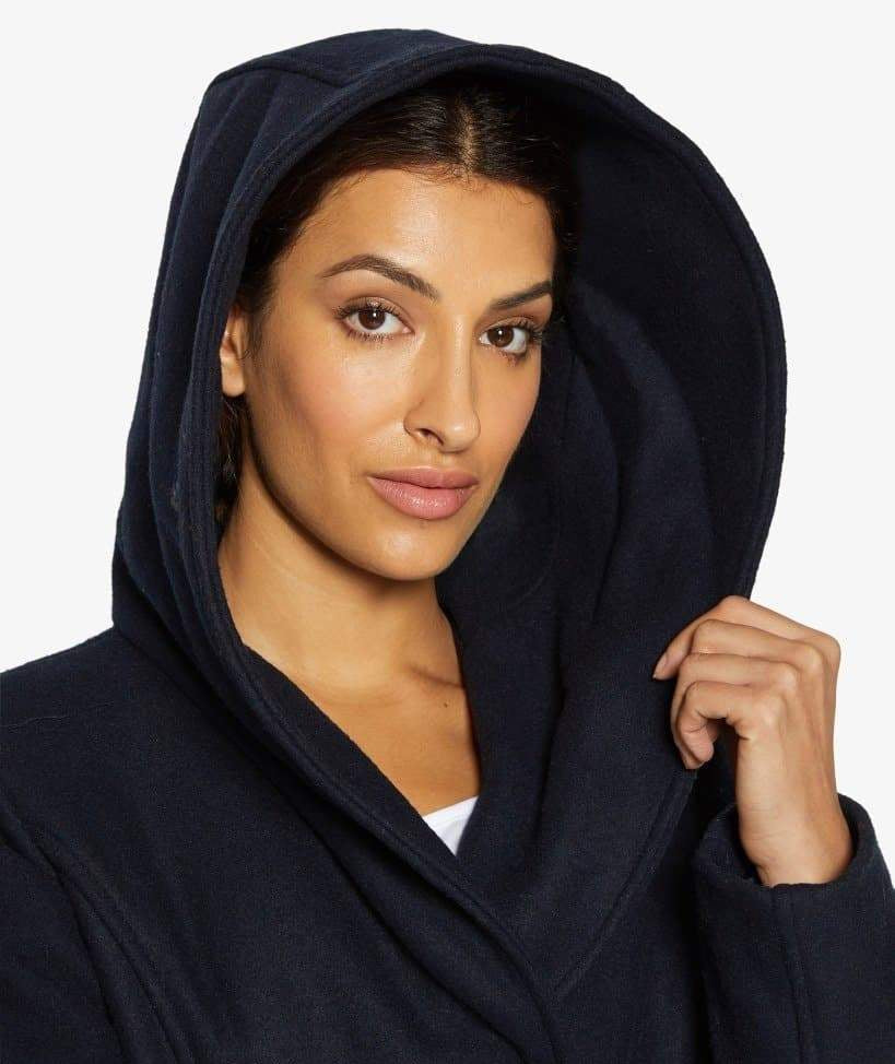 Woman wearing a navy blue hooded robe against a white background