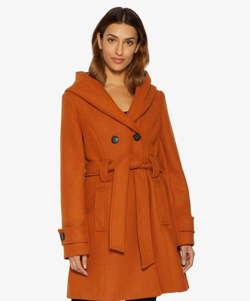 Woman wearing an orange coat with a hood on a white background