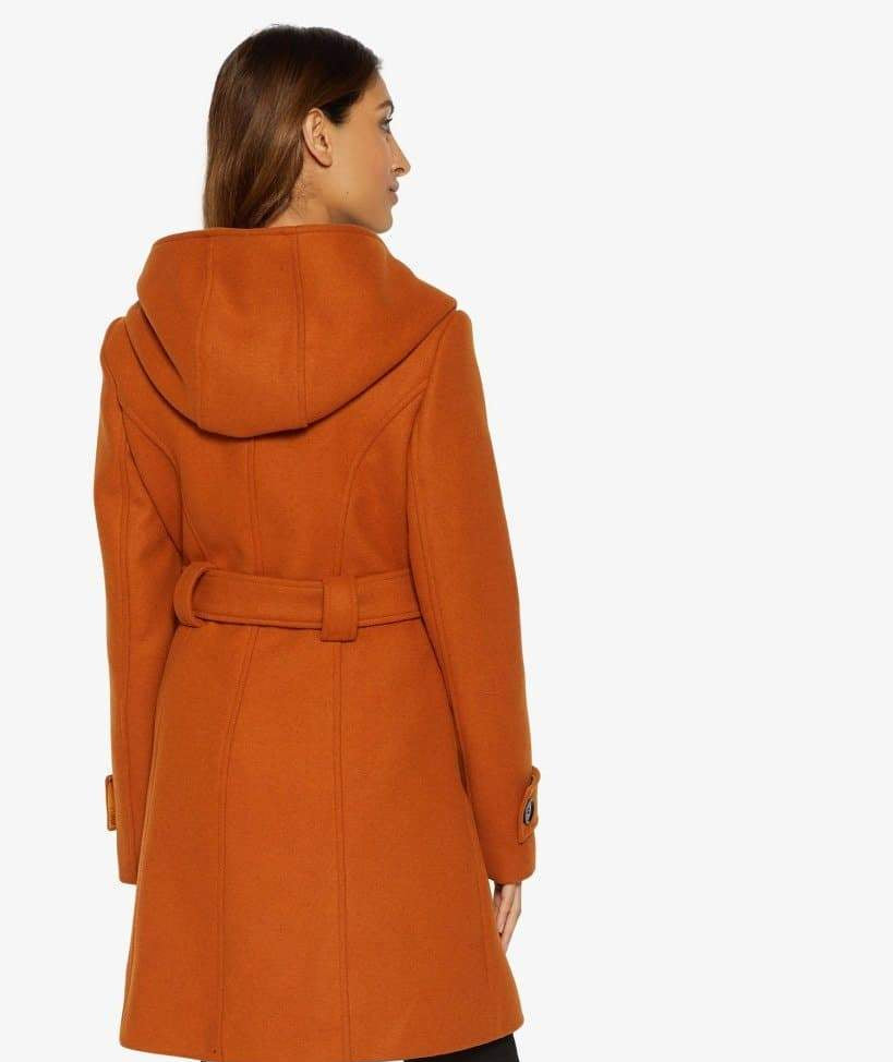 Woman wearing an orange coat with a hood on a white background