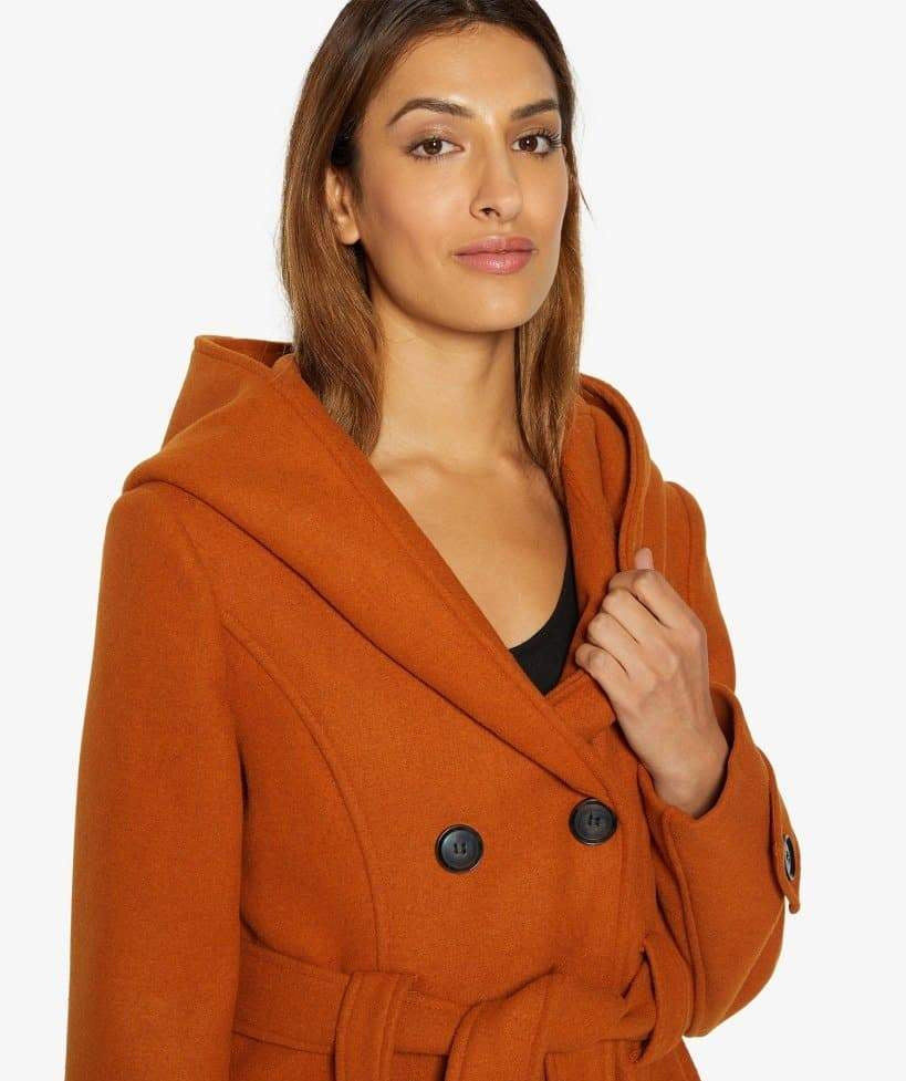 Woman wearing an orange coat with a hood on a white background