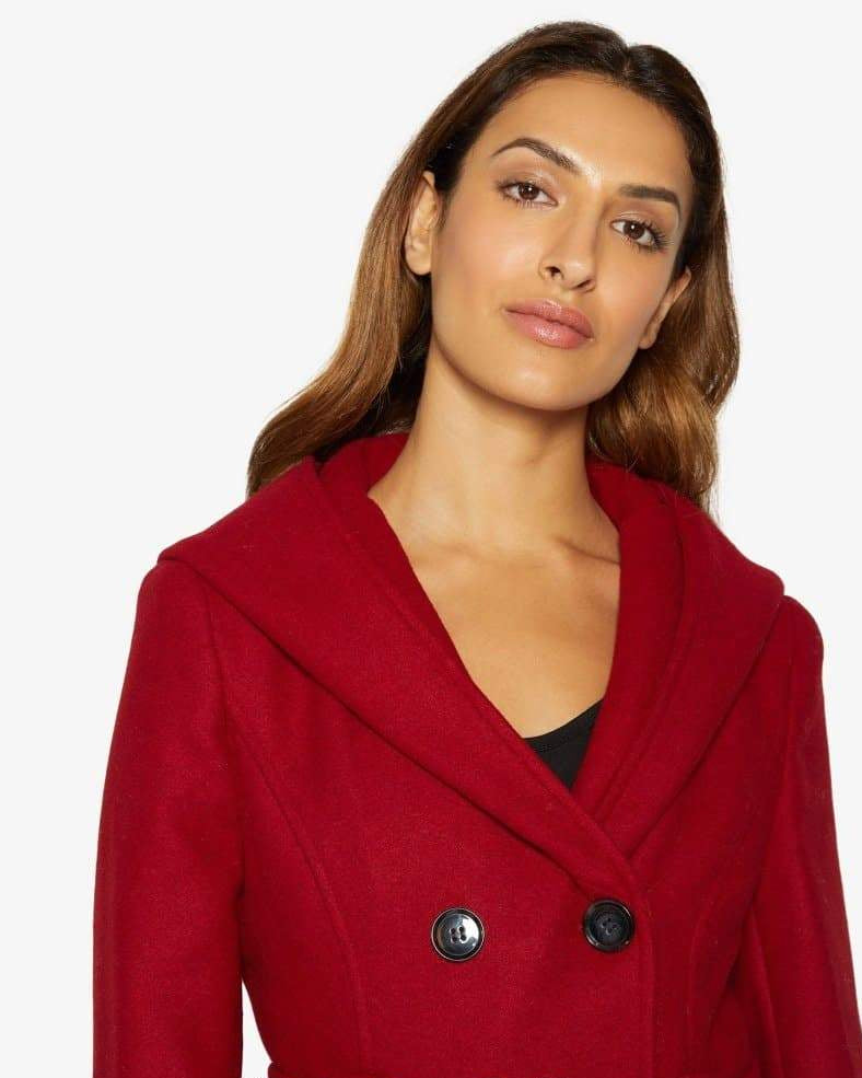 Woman wearing a red coat with black buttons on a white background.