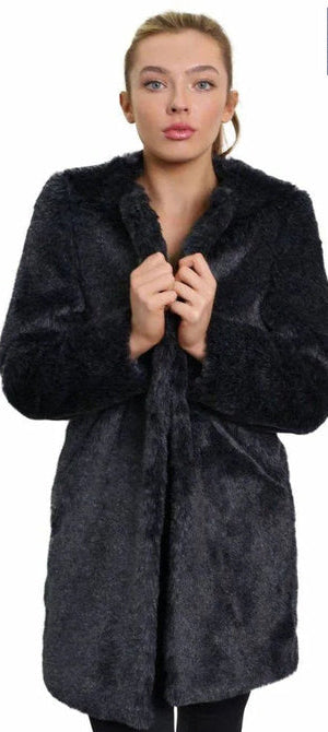 Woman wearing a black fur coat with a visible brand logo on a white background