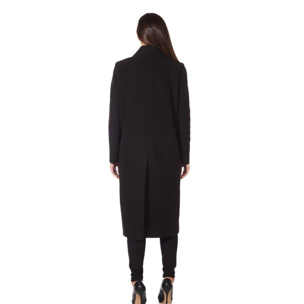 Woman wearing a long black coat on a white background