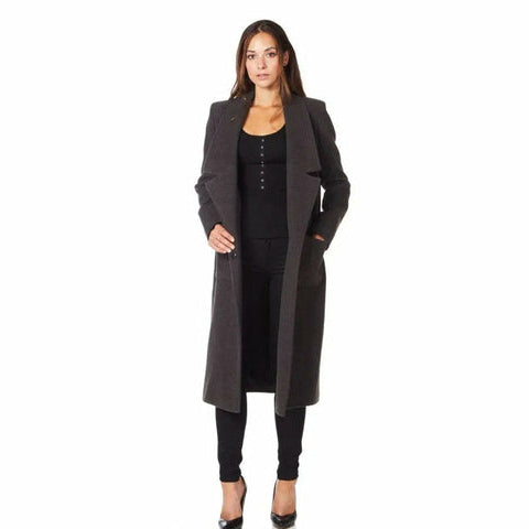 Woman wearing a long black coat over a black outfit on a white background