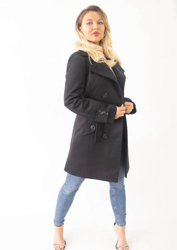 Woman wearing a black coat and blue jeans on a white background