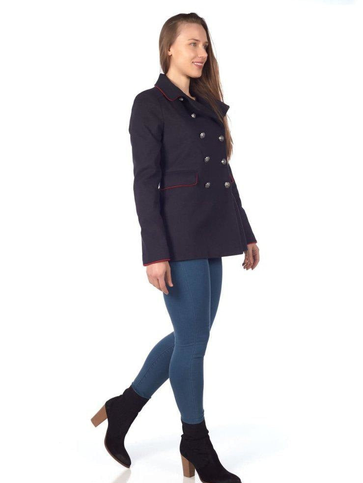 Woman wearing a navy blue coat with red trim on a white background