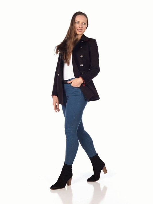 Woman wearing a black coat, white shirt, blue jeans, and black ankle boots on a white background