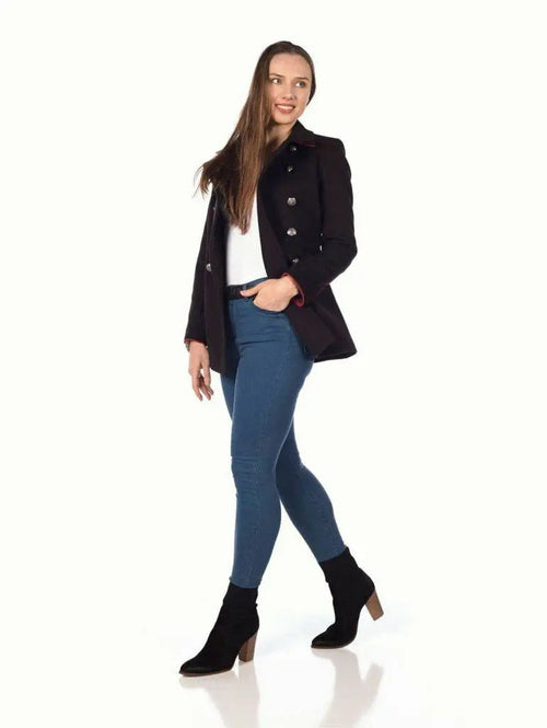 Woman wearing a black coat, white shirt, blue jeans, and black ankle boots on a white background