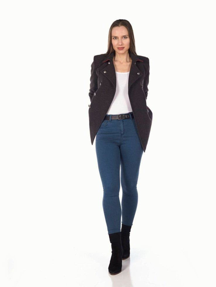Woman wearing a black jacket, white top, blue jeans, and black boots on a white background