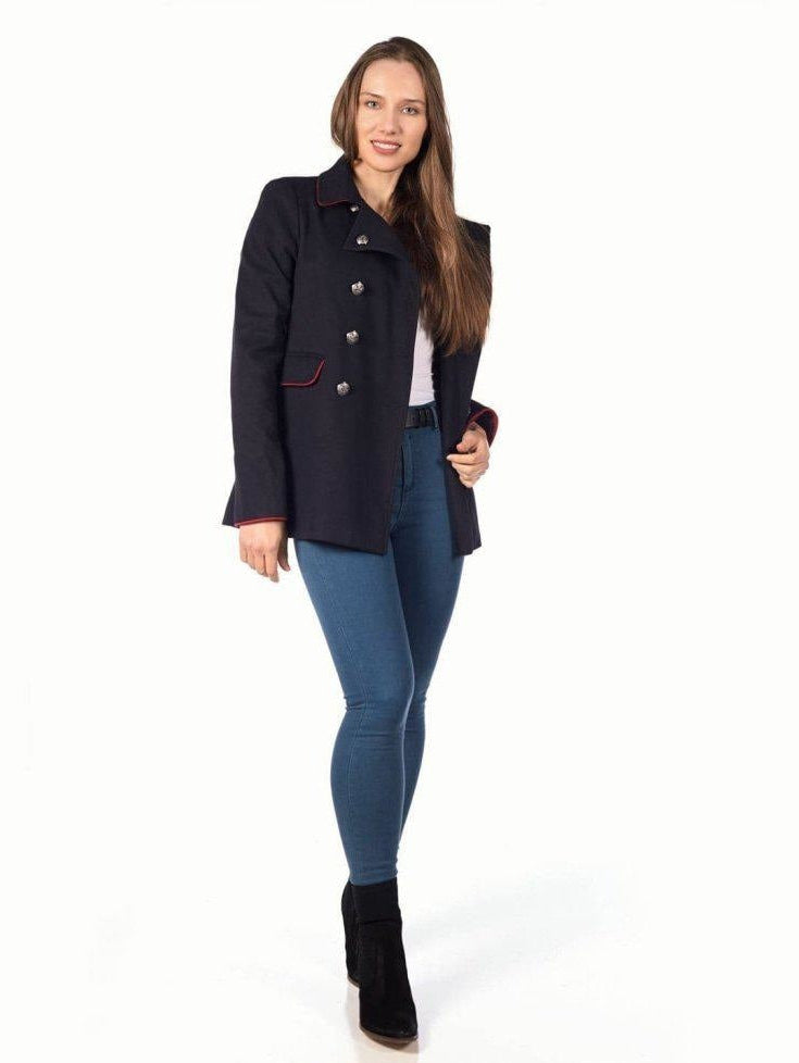 Woman wearing a navy peacoat, blue jeans, and black boots on a white background