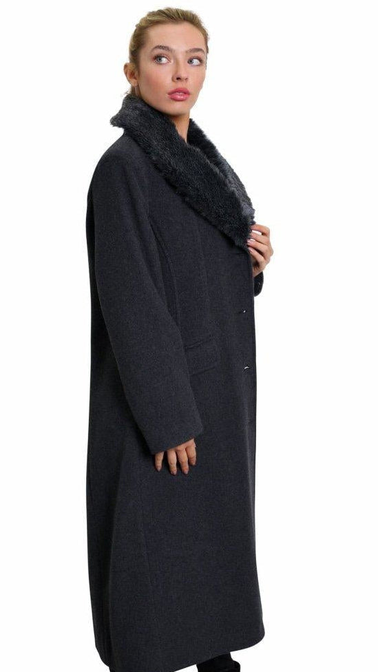 Woman wearing a long dark coat with a fur-lined hood on a white background