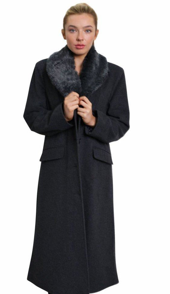 Woman wearing a long black coat with a fur collar on a white background