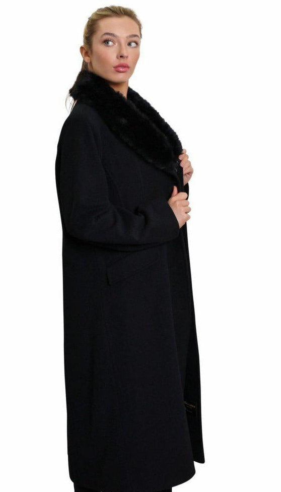 Woman wearing a long black coat with fur trim on a white background