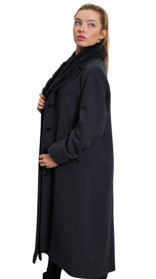 Woman wearing a long black coat on a white background