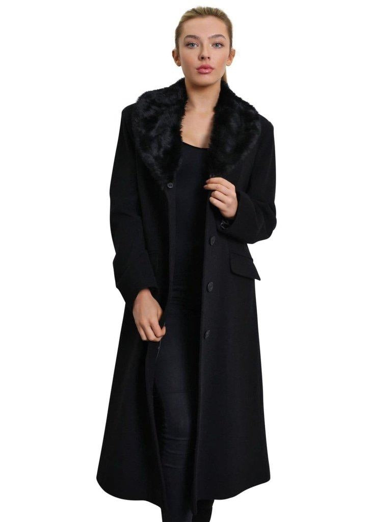 Woman wearing a long black coat with a fur collar on a white background