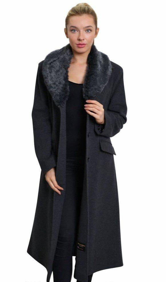 Woman wearing a long dark coat with fur collar on a white background
