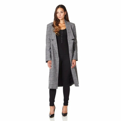 Woman wearing a long gray checkered coat over a black dress on a white background