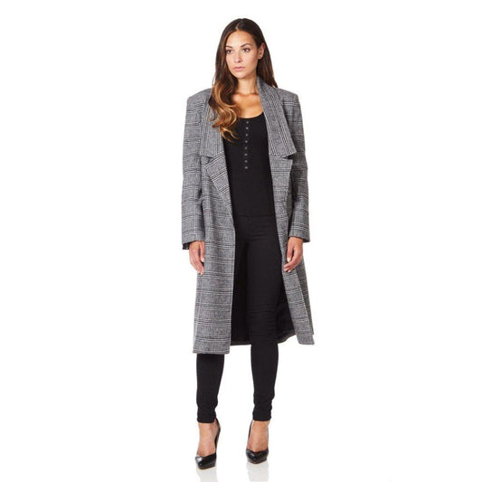 Woman wearing a long gray checkered coat over a black outfit on a white background