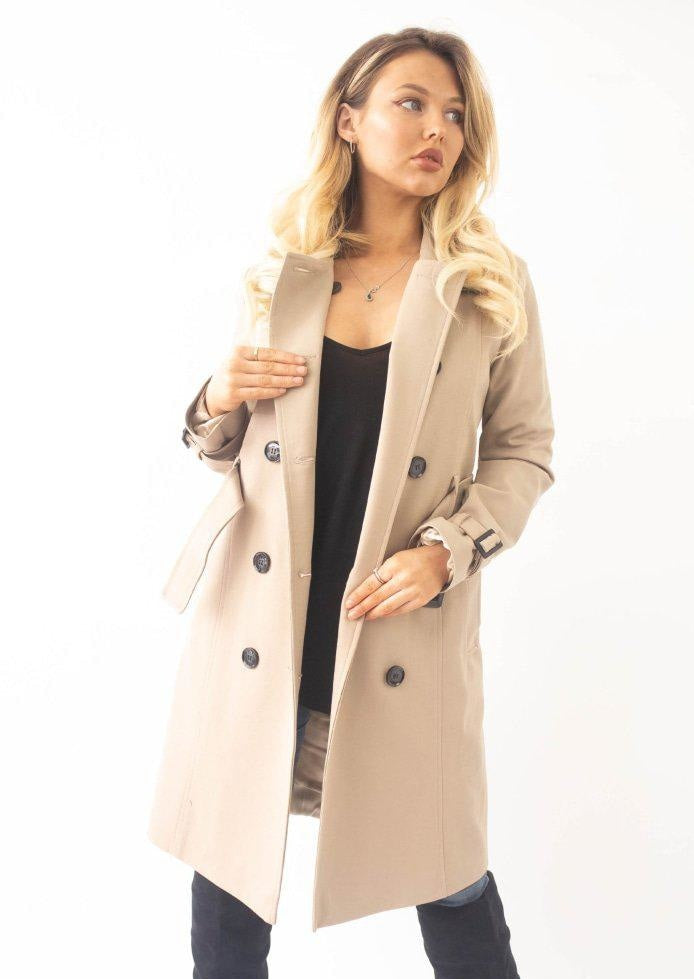 Woman wearing a beige trench coat on a white background