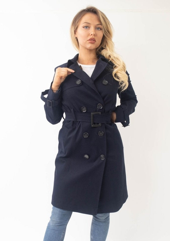 Woman wearing a navy blue trench coat on a white background