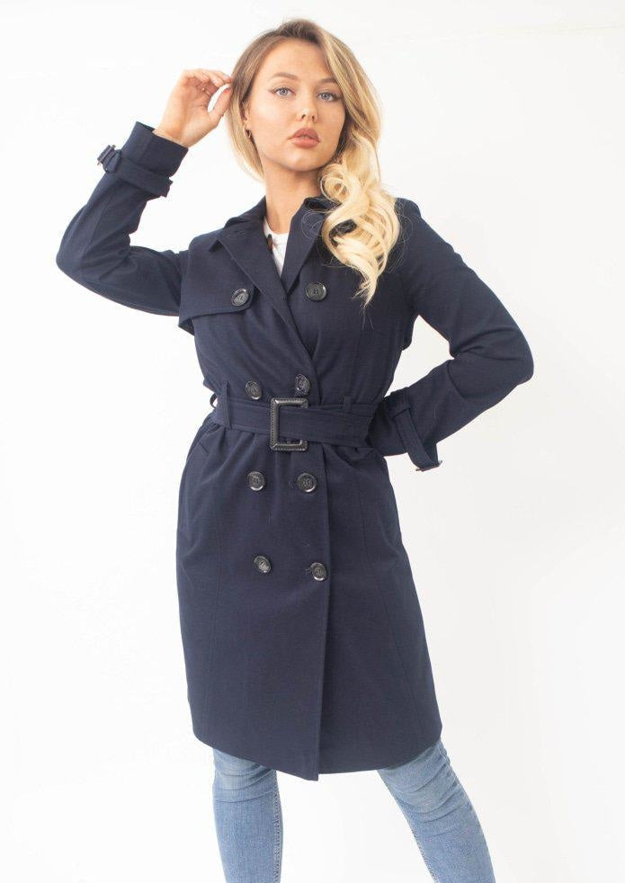 Woman wearing a navy blue trench coat on a white background