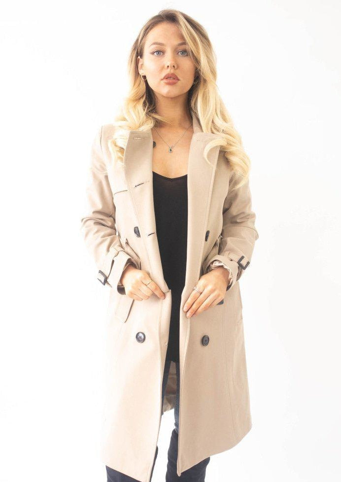 Woman wearing a beige trench coat on a white background