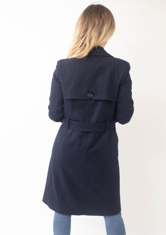 Person wearing a navy blue coat on a white background