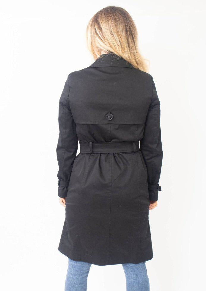 Woman wearing a black trench coat on a white background