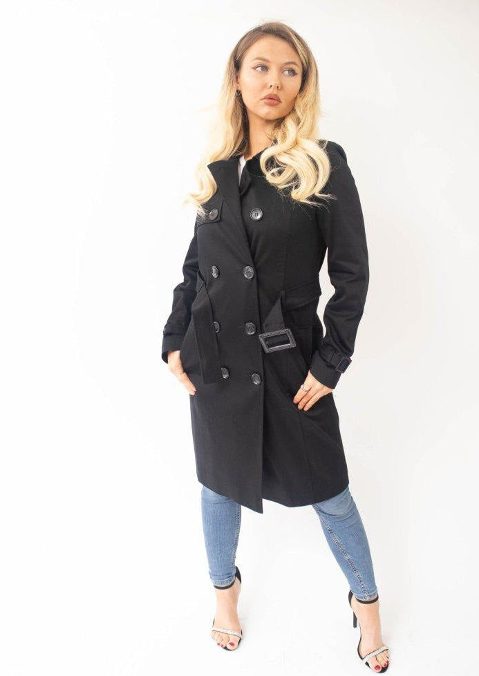Woman wearing a black trench coat with a white background