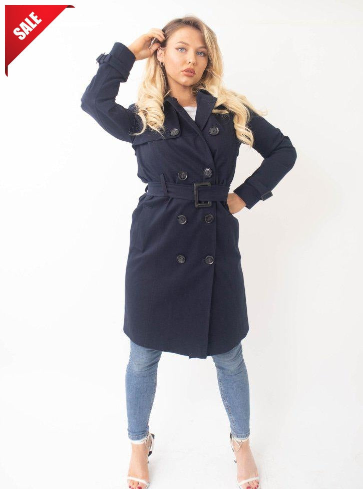 Woman wearing a navy blue trench coat on a white background